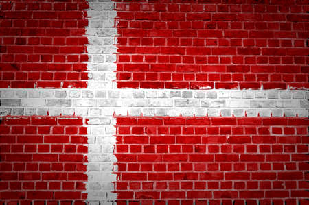An image of the Denmark flag painted on a brick wall in an urban locationの写真素材