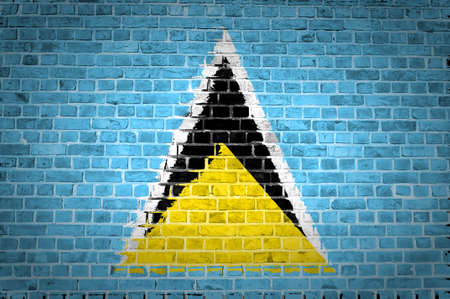 An image of the Saint Lucia flag painted on a brick wall in an urban locationの写真素材