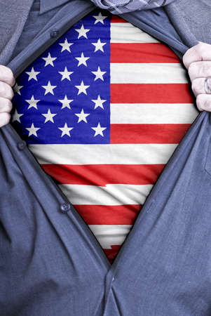 An American businessman rips open his shirt and shows how patriotic he is by revealing his countries flag beneath printed on a t-shirtの写真素材