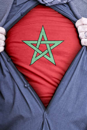 A Moroccan businessman rips open his shirt and shows how patriotic he is by revealing his countries flag beneath printed on a t-shirtの写真素材
