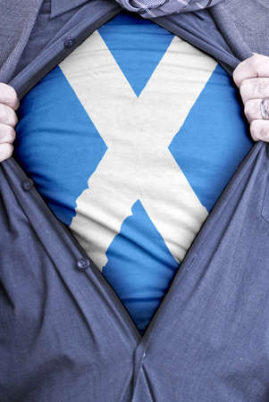 A Scottish businessman rips open his shirt and shows how patriotic he is by revealing his countries flag beneath printed on a t-shirtの写真素材