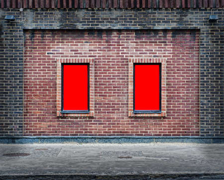 Two blank billboards attached to a buildings exterior brick wall.