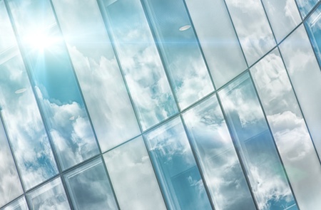 A close up shot of an average corporate buildings glass facade reflecting the sky.