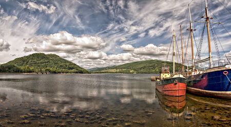 Two boats sit berthed on the scenic location of Loch Fyne at the Scottish town of Inverary.の写真素材