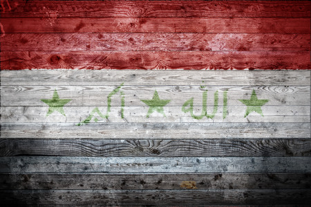 A vignetted background image of the flag of Iraq painted onto wooden boards of a wall or floor.の写真素材