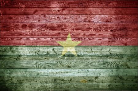 A vignetted background image of the flag of Burkina Faso painted onto wooden boards of a wall or floor.の写真素材