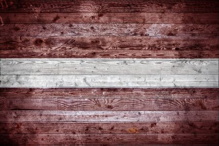 A vignetted background image of the flag of Latvia painted onto wooden boards of a wall or floor.の写真素材