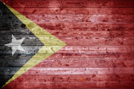 A vignetted background image of the flag of Timor Leste onto wooden boards of a wall or floor.の写真素材