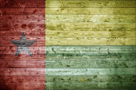 A vignetted background image of the flag of Guinea Bissau painted onto wooden boards of a wall or floor.の写真素材
