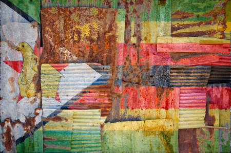 An abstract background image of the flag of Zimbabwe painted on to rusty corrugated iron sheets overlapping to form a wall or fence.の写真素材