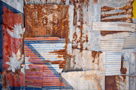 An abstract background image of the flag of Nepal painted on to rusty corrugated iron sheets overlapping to form a wall or fence.の写真素材