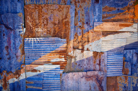 An abstract background image of the flag of Marshall Islands painted on to rusty corrugated iron sheets overlapping to form a wall or fence.の写真素材