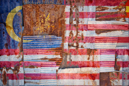 An abstract background image of the flag of Malaysia painted on to rusty corrugated iron sheets overlapping to form a wall or fence.の写真素材