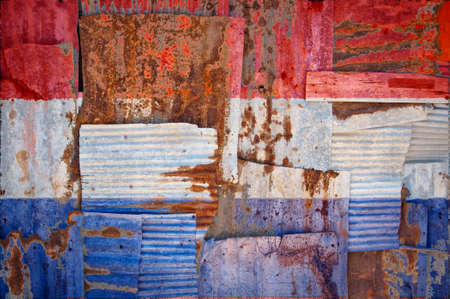 An abstract background image of the flag of Netherlands painted on to rusty corrugated iron sheets overlapping to form a wall or fence.の写真素材