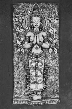 Carving in Thailand of a naked religious woman praying or meditating