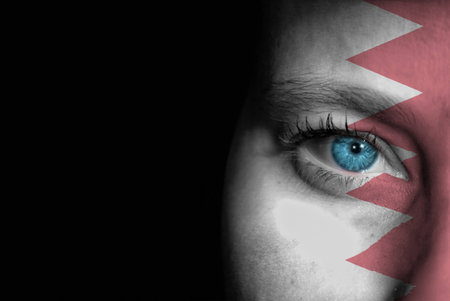 A young female with the flag of Bahrain painted on her face on her way to a sporting event to show her support.の写真素材