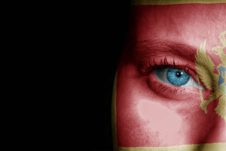 A young female with the flag of Montenegro painted on her face on her way to a sporting event to show her support.の写真素材