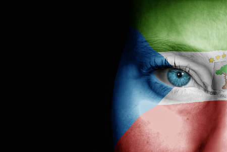 A young female with the flag of Equatorial Guinea painted on her face on her way to a sporting event to show her support.の写真素材