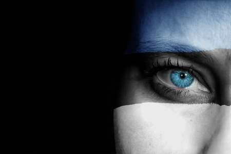 A young female with the flag of Estonia painted on her face on her way to a sporting event to show her support.の写真素材