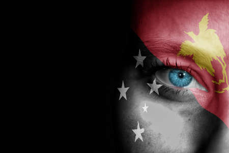 A young female with the flag of Papua New Guinea painted on her face on her way to a sporting event to show her support.の写真素材