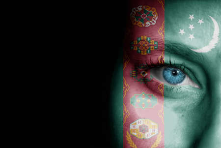 A young female with the flag of Turkmenistan painted on her face on her way to a sporting event to show her support.の写真素材