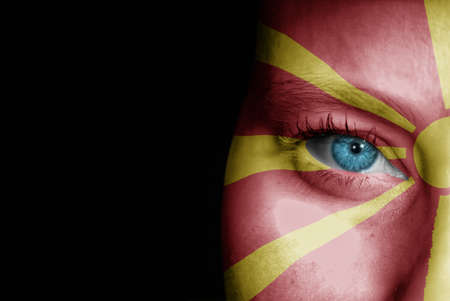 A young female with the flag of Macedonia painted on her face on her way to a sporting event to show her support.の写真素材
