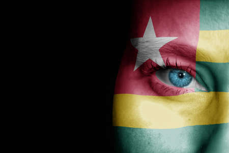 A young female with the flag of Togo painted on her face on her way to a sporting event to show her support.の写真素材