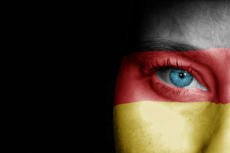 A young female with the flag of Germany painted on her face on her way to a sporting event to show her support.の写真素材