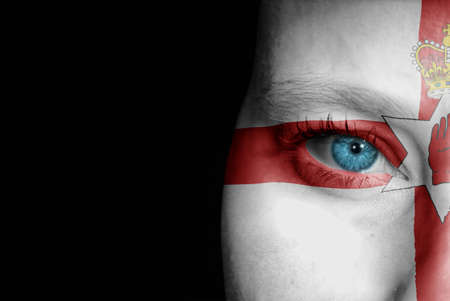 A young female with the flag of Northern Ireland painted on her face on her way to a sporting event to show her support.の写真素材