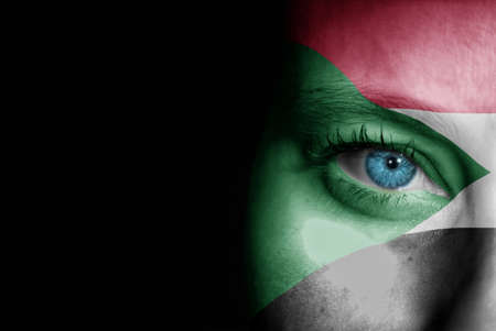 A young female with the flag of Sudan painted on her face on her way to a sporting event to show her support.の写真素材