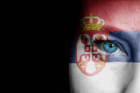 A young female with the flag of Serbia painted on her face on her way to a sporting event to show her support.の写真素材