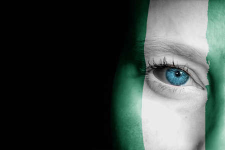 A young female with the flag of Nigeria painted on her face on her way to a sporting event to show...