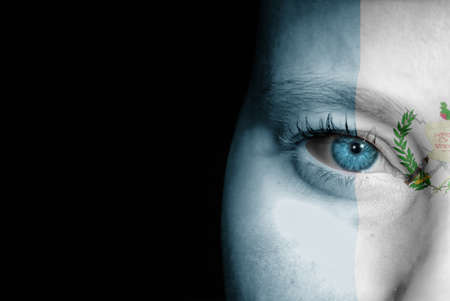 A young female with the flag of Guatemala painted on her face on her way to a sporting event to show her support.の写真素材
