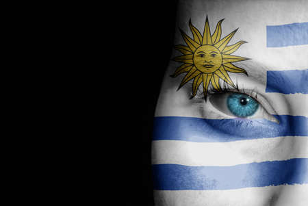 A young female with the flag of Uruguay painted on her face on her way to a sporting event to show her support.の写真素材