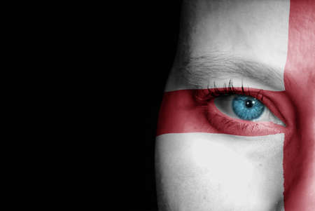 A young female with the flag of England painted on her face on her way to a sporting event to show her support.の写真素材