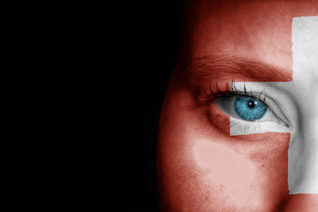 A young female with the flag of Switzerland painted on her face on her way to a sporting event to show her support.の写真素材