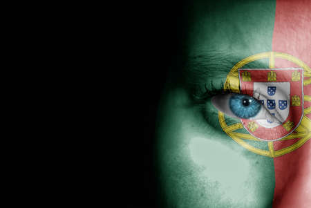 A young female with the flag of Portugal painted on her face on her way to a sporting event to show her support.の写真素材