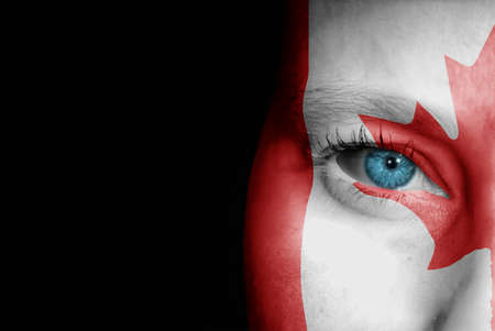 A young female with the flag of Canada painted on her face on her way to a sporting event to show her support.の写真素材