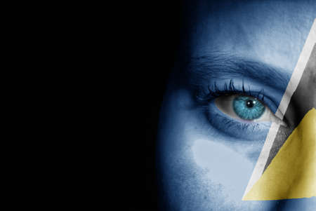 A young female with the flag of St Lucia painted on her face on her way to a sporting event to show her support.の写真素材