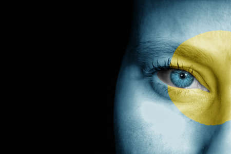 A young female with the flag of Palau painted on her face on her way to a sporting event to show her support.の写真素材