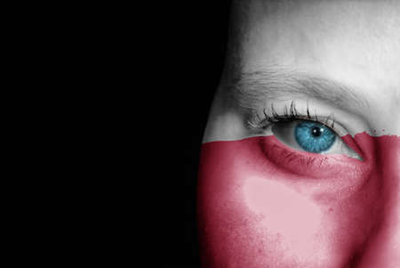 A young female with the flag of Poland painted on her face on her way to a sporting event to show her support.の写真素材