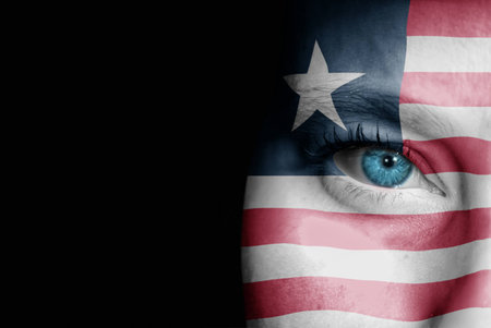 A young female with the flag of Liberia painted on her face on her way to a sporting event to show her support.の写真素材