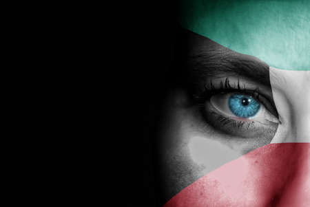 A young female with the flag of Kuwait painted on her face on her way to a sporting event to show her support.の写真素材