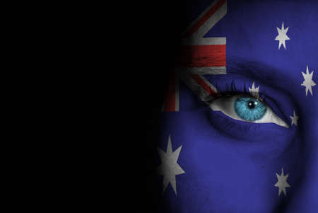 A young female with the flag of Australia painted on her face on her way to a sporting event to show her support.の写真素材