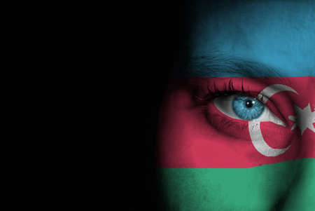 A young female with the flag of Azerbaijan painted on her face on her way to a sporting event to show her support.の写真素材