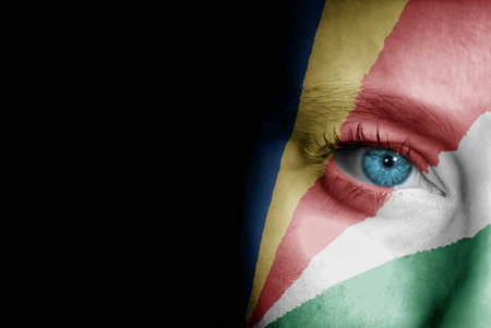 A young female with the flag of Seychelles painted on her face on her way to a sporting event to show her support.の写真素材