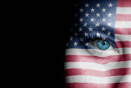 A young female with the flag of United States of America painted on her face on her way to a sporting event to show her support.の写真素材