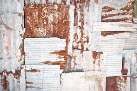 An abstract background image of rusting white corrugated iron sheets overlapping to form a wall or fence.の写真素材