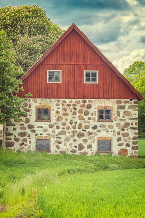 An old stone barn with wooden roof set in the rural countryside of Swedens Skane region.の写真素材