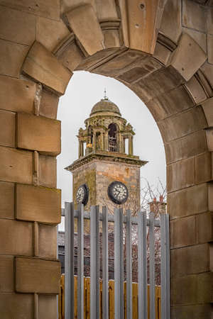 A view of the town hall clock tower in Clydebank through a nearby archway.